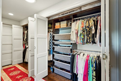 Mid-sized trendy gender-neutral medium tone wood floor and brown floor reach-in closet photo in Seattle with recessed-panel cabinets and white cabinets