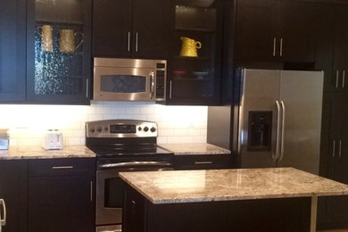 Mid-sized transitional l-shaped light wood floor enclosed kitchen photo in Other with an undermount sink, shaker cabinets, dark wood cabinets, granite countertops, beige backsplash, subway tile backsplash, stainless steel appliances and an island