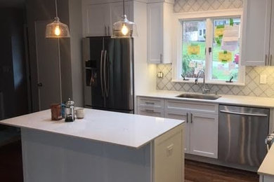 Example of a mid-sized minimalist u-shaped dark wood floor and brown floor eat-in kitchen design in New York with an undermount sink, recessed-panel cabinets, white cabinets, quartzite countertops, white backsplash, ceramic backsplash, stainless steel appliances, a peninsula and white countertops