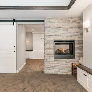 Inspiration for a large traditional look-out basement in Minneapolis with grey walls, carpet, a two-sided fireplace, a stone fireplace surround and grey floors.