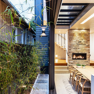 Inspiration for a contemporary dining room in Sydney with white walls, concrete floors, a ribbon fireplace, a brick fireplace surround and white floor.