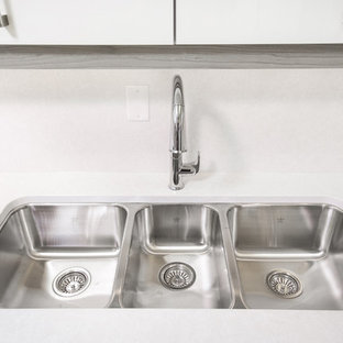 Inspiration for a large contemporary u-shaped kitchen pantry in Toronto with a triple-bowl sink, flat-panel cabinets, white cabinets, quartz benchtops, white splashback, stone slab splashback, stainless steel appliances and multiple islands.