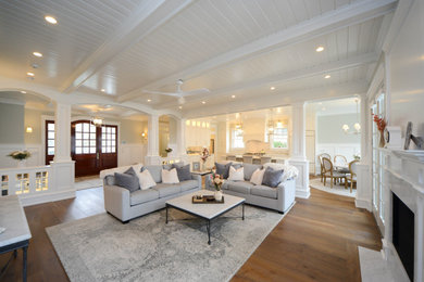 This is an example of a beach style formal open concept living room in Philadelphia with white walls, medium hardwood floors, a standard fireplace, brown floor, exposed beam, timber and decorative wall panelling.