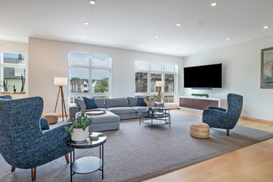Imagen de salón tipo loft con paredes blancas, suelo de madera clara y televisor independiente