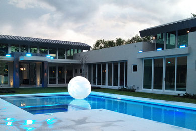 Modelo de piscinas y jacuzzis alargados modernos de tamaño medio rectangulares en patio trasero con losas de hormigón