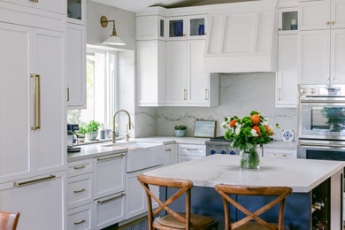 Example of a mid-sized classic medium tone wood floor kitchen design in San Diego with a farmhouse sink, shaker cabinets, white cabinets, quartzite countertops, white backsplash, stone slab backsplash, paneled appliances, an island and white countertops