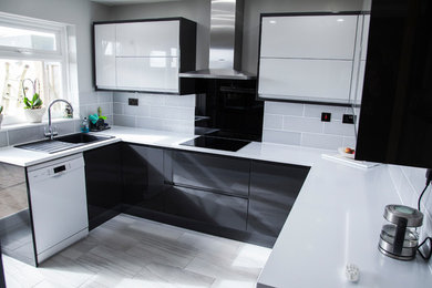 Ejemplo de cocinas en U moderno de tamaño medio con armarios con paneles lisos, puertas de armario grises y salpicadero negro