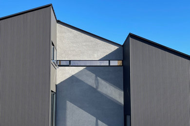 Imagen de fachada de casa negra y negra minimalista de dos plantas con revestimiento de metal, tejado a dos aguas y tejado de metal