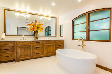 Inspiration for a mediterranean master white tile white floor and limestone floor freestanding bathtub remodel in Los Angeles with raised-panel cabinets, medium tone wood cabinets, white walls, an undermount sink and quartz countertops