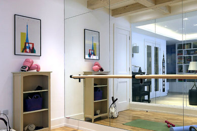 This is an example of a contemporary home gym in London with white walls, medium hardwood floors and brown floor.