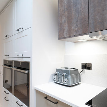 A simple freestanding microwave is hidden behind a door above the oven