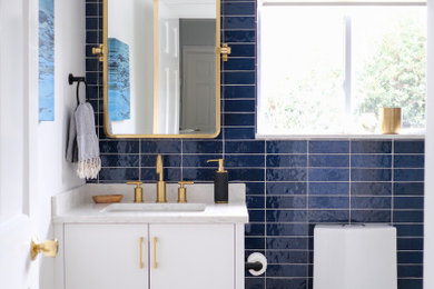 Corner shower - small contemporary blue tile and subway tile marble floor, beige floor and single-sink corner shower idea in New York with flat-panel cabinets, white cabinets, white walls, an undermount sink, quartz countertops, a hinged shower door, gray countertops and a freestanding vanity