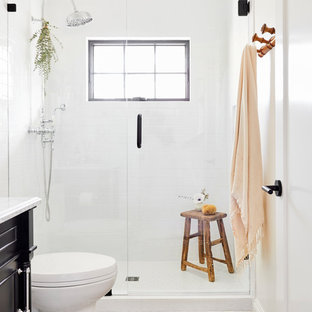 Inspiration for a medium sized mediterranean shower room bathroom in Los Angeles with freestanding cabinets, black cabinets, an alcove shower, a two-piece toilet, white tiles, ceramic tiles, white walls, cement flooring, a submerged sink, marble worktops, white floors, a hinged door and white worktops.