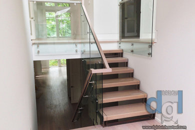 Medium sized contemporary wood straight mixed railing staircase in Toronto with open risers.