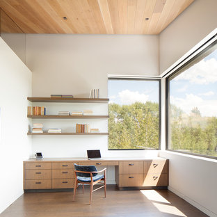 Modern study in Other with white walls, medium hardwood flooring and a built-in desk.