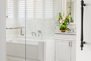 This is an example of a large transitional master bathroom in Seattle with raised-panel cabinets, white cabinets, an alcove tub, a shower/bathtub combo, a one-piece toilet, white tile, marble, white walls, porcelain floors, an undermount sink, engineered quartz benchtops, beige floor, a hinged shower door and beige benchtops.