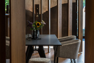 Mittelgroßes, Repräsentatives, Abgetrenntes Modernes Wohnzimmer mit schwarzer Wandfarbe, braunem Holzboden, braunem Boden und Tapetenwänden in München