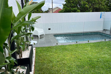 Mid-sized modern backyard rectangular pool in Sydney with with a pool and natural stone pavers.