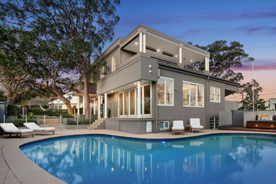 This is an example of a large contemporary backyard kidney-shaped pool in Sydney with with a pool and concrete pavers.