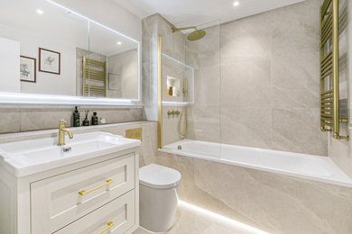 Inspiration for a modern family bathroom in London with shaker cabinets, a built-in bath, a shower/bath combination, a wall mounted toilet, ceramic flooring, a dado rail, a single sink and a freestanding vanity unit.