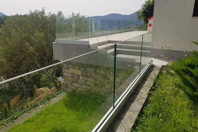 Immagine di una terrazza design dietro casa con un tetto a sbalzo e parapetto in vetro