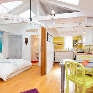 Aménagement d'une chambre éclectique avec un mur blanc, un sol en bois clair et un sol jaune.