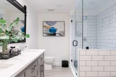 Cette photo montre une petite salle de bain moderne pour enfant avec des portes de placard grises, un sol en carrelage de porcelaine, un lavabo encastré, un plan de toilette en quartz, un sol gris, une cabine de douche à porte battante, un plan de toilette blanc, meuble double vasque et meuble-lavabo encastré.