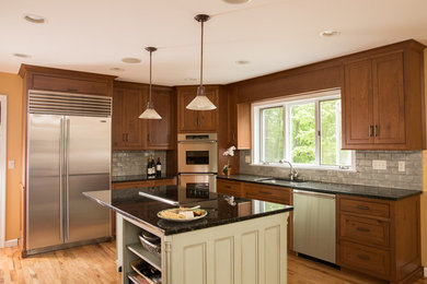 Large elegant medium tone wood floor and brown floor kitchen photo in New York with beaded inset cabinets, medium tone wood cabinets, granite countertops, stainless steel appliances, an island, gray backsplash and subway tile backsplash