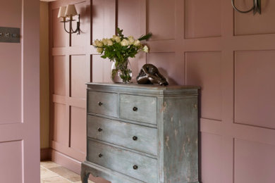 Inspiration for a mid-sized cottage limestone floor, beige floor and exposed beam entryway remodel in Surrey with pink walls and a medium wood front door