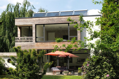 Photo of a mid-sized contemporary two-storey brown house exterior in Cologne with wood siding and a flat roof.