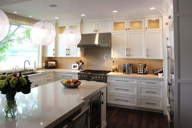 Inspiration for a large transitional u-shaped dark wood floor eat-in kitchen remodel in Other with a single-bowl sink, flat-panel cabinets, white cabinets, solid surface countertops, white backsplash, subway tile backsplash, stainless steel appliances and an island