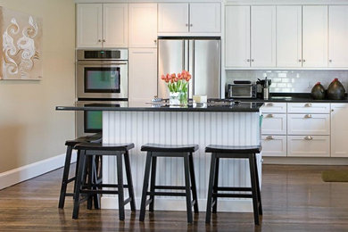 Kitchen - mid-sized transitional single-wall medium tone wood floor kitchen idea in Los Angeles with an undermount sink, shaker cabinets, white cabinets, granite countertops, white backsplash, subway tile backsplash, stainless steel appliances and an island
