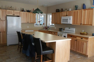 Example of a mid-sized transitional l-shaped linoleum floor eat-in kitchen design in Seattle with a double-bowl sink, recessed-panel cabinets, light wood cabinets, laminate countertops, beige backsplash, white appliances and an island
