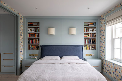 Design ideas for a large contemporary guest bedroom in London with blue walls, light hardwood flooring, no fireplace, blue floors and feature lighting.