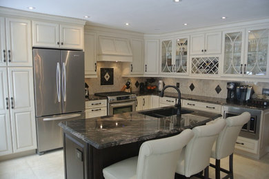 Inspiration for a mid-sized timeless l-shaped porcelain tile and beige floor eat-in kitchen remodel in Toronto with an undermount sink, raised-panel cabinets, granite countertops, an island, white cabinets, multicolored backsplash, marble backsplash and stainless steel appliances