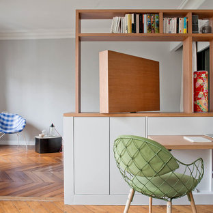 Idéer för små funkis hemmabibliotek, med grå väggar, mellanmörkt trägolv och ett inbyggt skrivbord