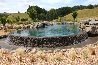 Inspiration for a large tropical backyard custom-shaped pool in Auckland with a hot tub.