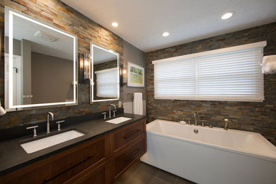 This is an example of a mid-sized arts and crafts master bathroom in Other with shaker cabinets, dark wood cabinets, a freestanding tub, an alcove shower, a two-piece toilet, beige tile, stone tile, brown walls, porcelain floors, an undermount sink, granite benchtops, brown floor, a hinged shower door, black benchtops, a niche, a double vanity and a floating vanity.