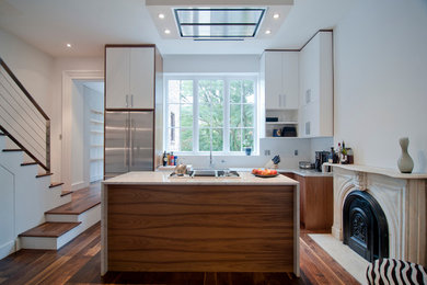 Example of a transitional galley open concept kitchen design in New York with flat-panel cabinets, white cabinets, white backsplash and stainless steel appliances