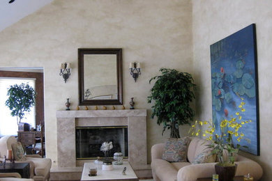 Photo of a mid-sized mediterranean formal open concept living room in San Francisco with beige walls, medium hardwood floors, a standard fireplace, a concrete fireplace surround, no tv and brown floor.