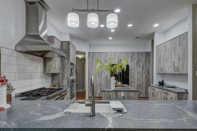 Example of a mid-sized minimalist kitchen design in Houston with a drop-in sink, flat-panel cabinets, gray cabinets, quartz countertops, white backsplash, ceramic backsplash, stainless steel appliances, an island and gray countertops
