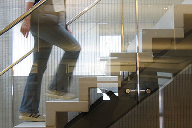 ニューヨークにあるコンテンポラリースタイルのおしゃれなスケルトン階段 (コンクリートの蹴込み板、ガラスフェンス) の写真