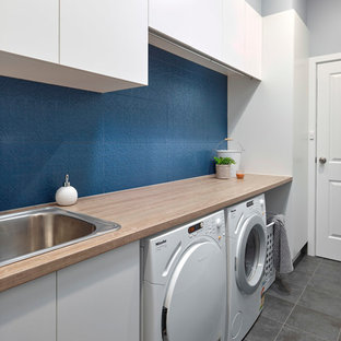 Small contemporary single-wall separated utility room in Adelaide with a built-in sink, flat-panel cabinets, white cabinets, laminate countertops, blue walls, porcelain flooring, a side by side washer and dryer, grey floors and orange worktops.
