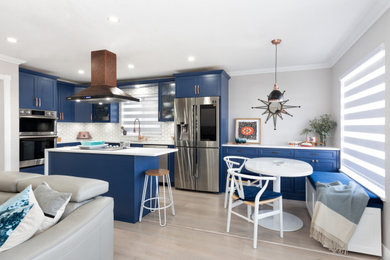 Mid-sized transitional l-shaped laminate floor and beige floor open concept kitchen photo in Vancouver with a single-bowl sink, shaker cabinets, blue cabinets, quartzite countertops, white backsplash, ceramic backsplash, stainless steel appliances, an island and white countertops