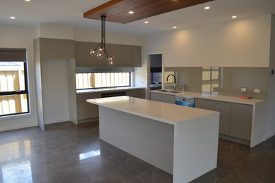 Photo of a large contemporary kitchen in Melbourne with an undermount sink, grey cabinets, quartz benchtops, stainless steel appliances, porcelain floors, with island and white benchtop.