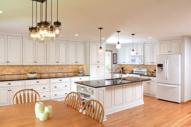 Example of a large trendy l-shaped light wood floor and beige floor eat-in kitchen design in Chicago with a double-bowl sink, raised-panel cabinets, white cabinets, beige backsplash, ceramic backsplash, white appliances and an island