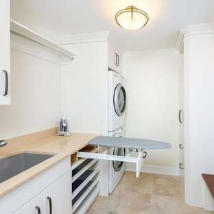 Inspiration for a small classic single-wall separated utility room in Toronto with a submerged sink, flat-panel cabinets, white cabinets, engineered stone countertops, white walls, marble flooring and a stacked washer and dryer.