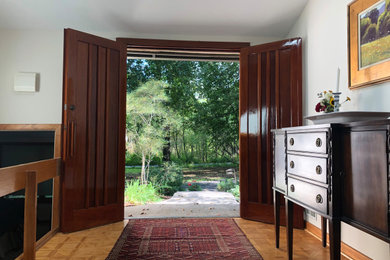 Huge 1960s light wood floor and multicolored floor entryway photo in New York with beige walls and a dark wood front door
