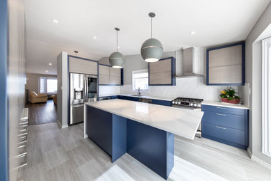 Mid-sized minimalist l-shaped vinyl floor and gray floor enclosed kitchen photo in Calgary with a double-bowl sink, flat-panel cabinets, blue cabinets, granite countertops, white backsplash, ceramic backsplash, stainless steel appliances, an island and white countertops