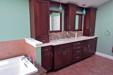 Large transitional master ceramic tile double-sink, ceramic tile, red floor and vaulted ceiling bathroom photo in Philadelphia with raised-panel cabinets, brown cabinets, quartz countertops, beige countertops, a built-in vanity, green walls, an undermount sink, a hinged shower door and a two-piece toilet